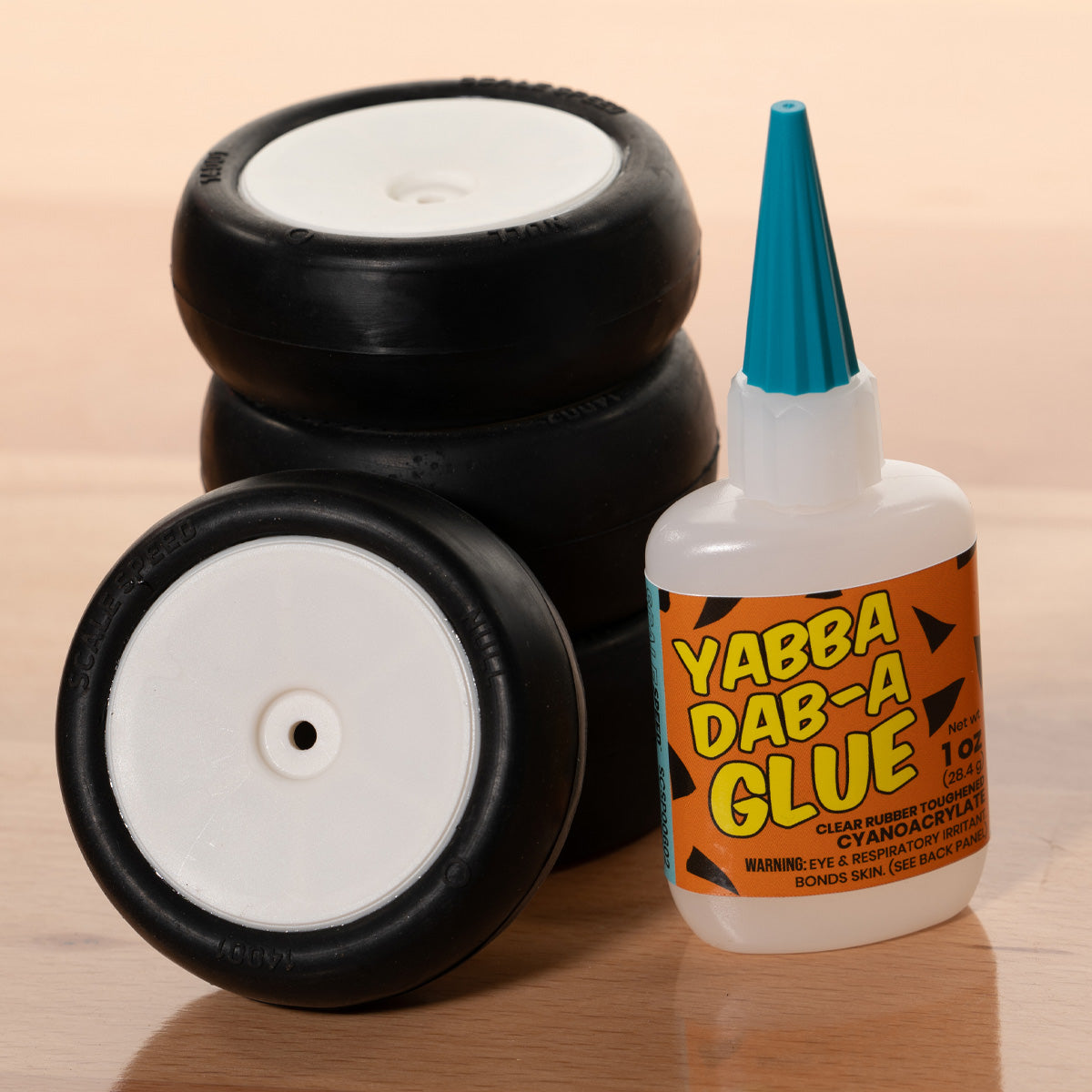 RC wheels and a bottle of Yabba Dab-A Glue on a wood table background