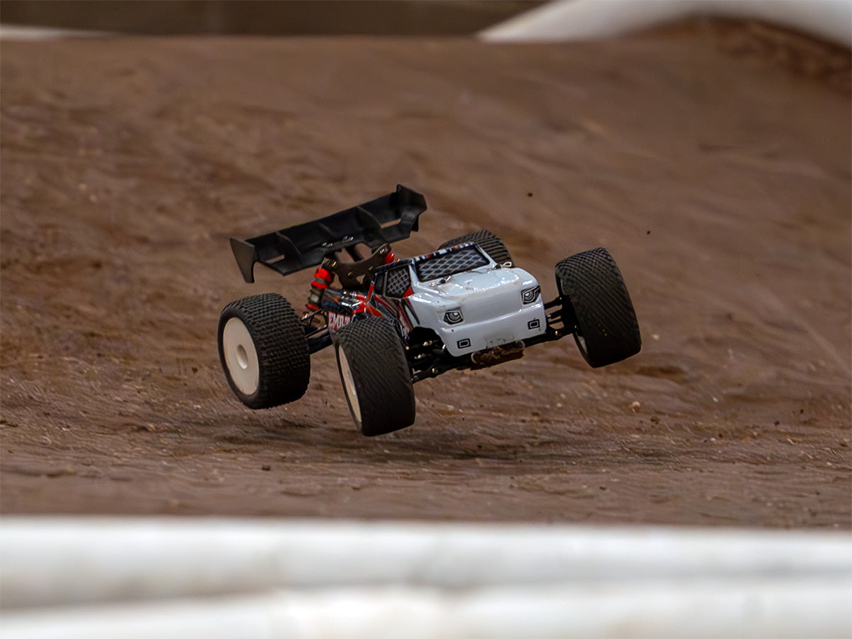 LC Racing EMB-TG truggy on clay track, jumping in air, front view
